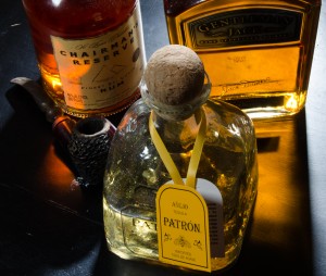 Tequila, bourbon and rum bottles on black table with light glowing through them.